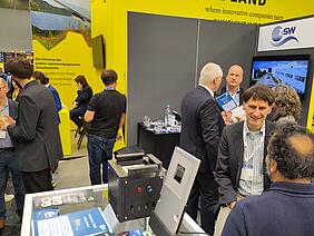 Blick auf den Messestand vom ZSW, auf dem sich viele Leute unterhalten.